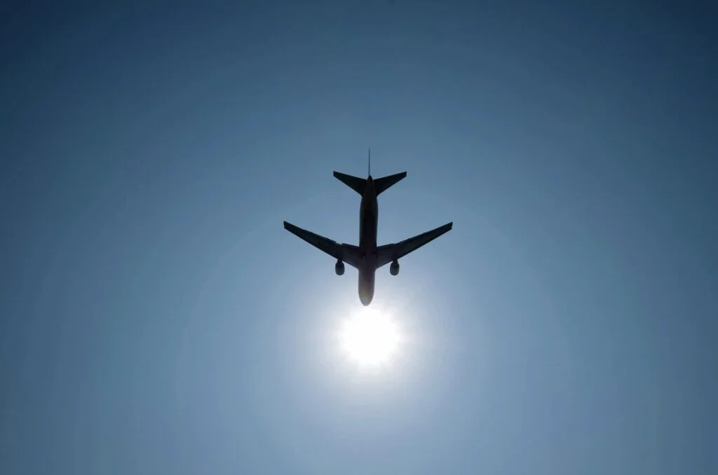 airplane in a blue sky with bright sun shining
