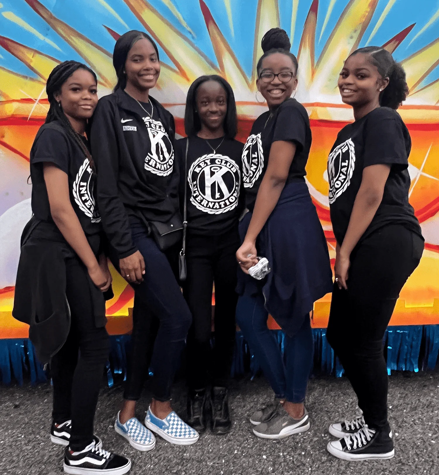 5 students standing in front of a painted mural